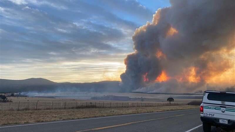 Hermits Peak fire in New Mexico, with white Forest Service pickup truck in foreground.