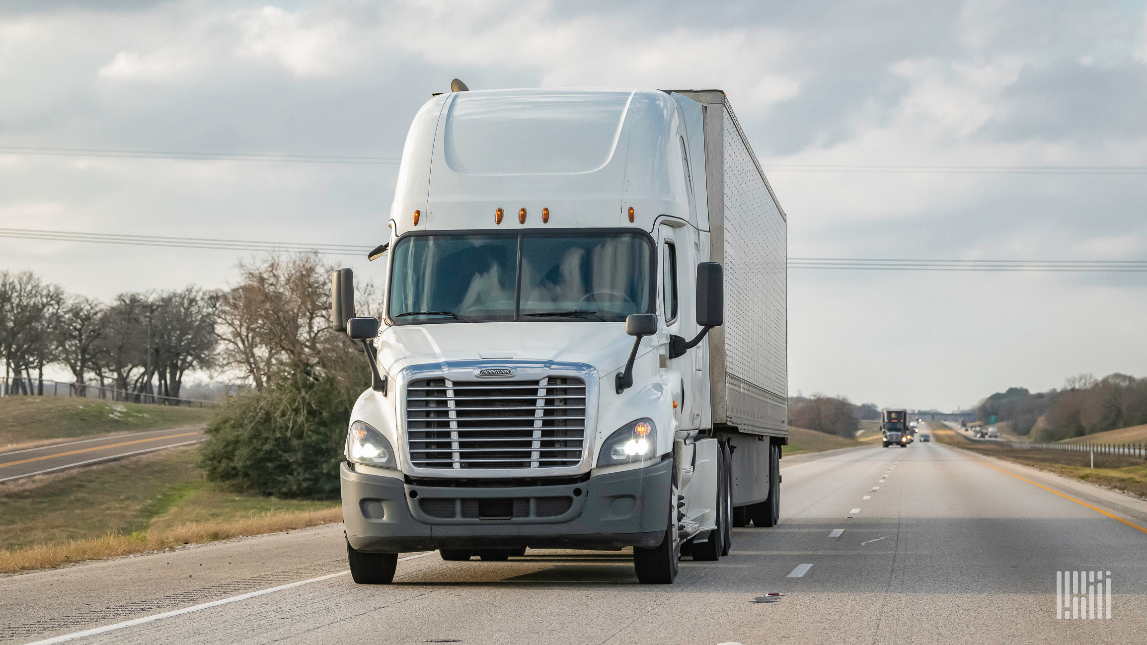 White tractor trailer truck driving toward camera