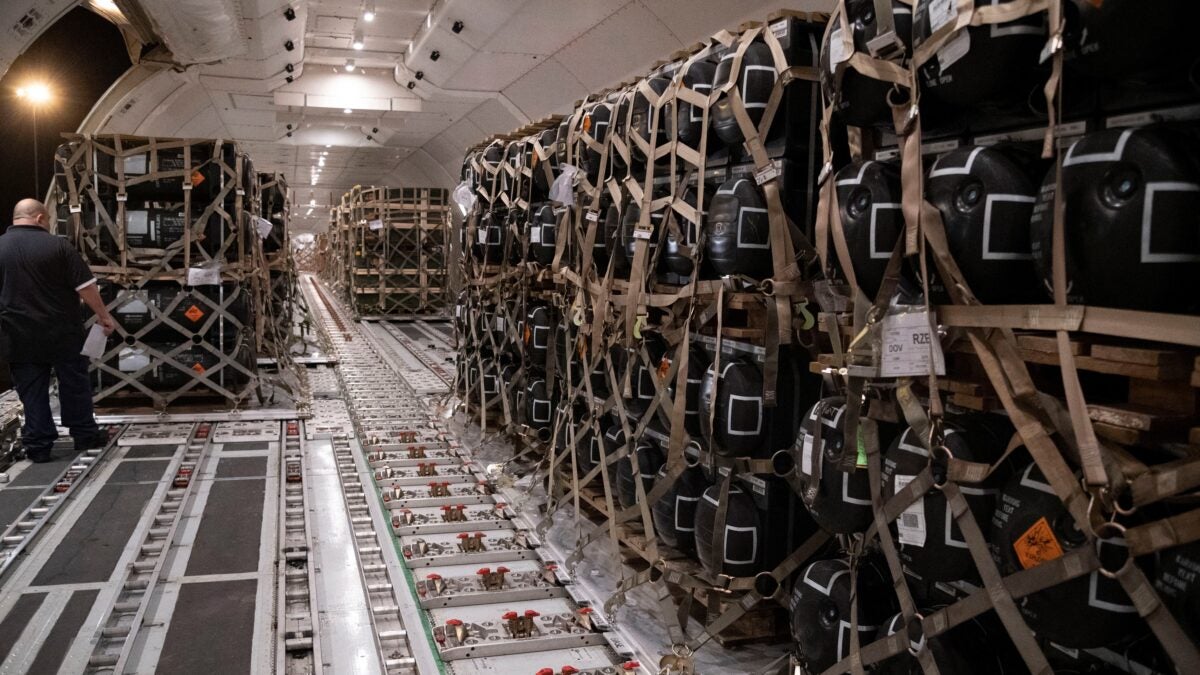 Pallets containing ammunition, explosives and other supplies are loaded into a cargo plane.