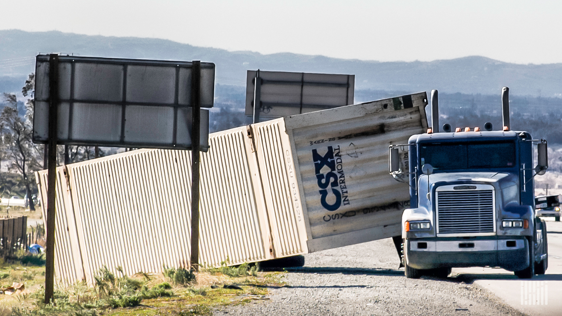 White CSX trailer tipped over onto side of a highway.