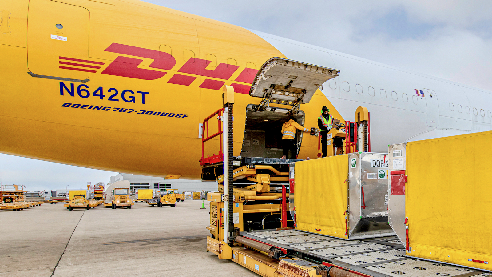 A cargo plane with the logo of is unloaded by men at an airport.