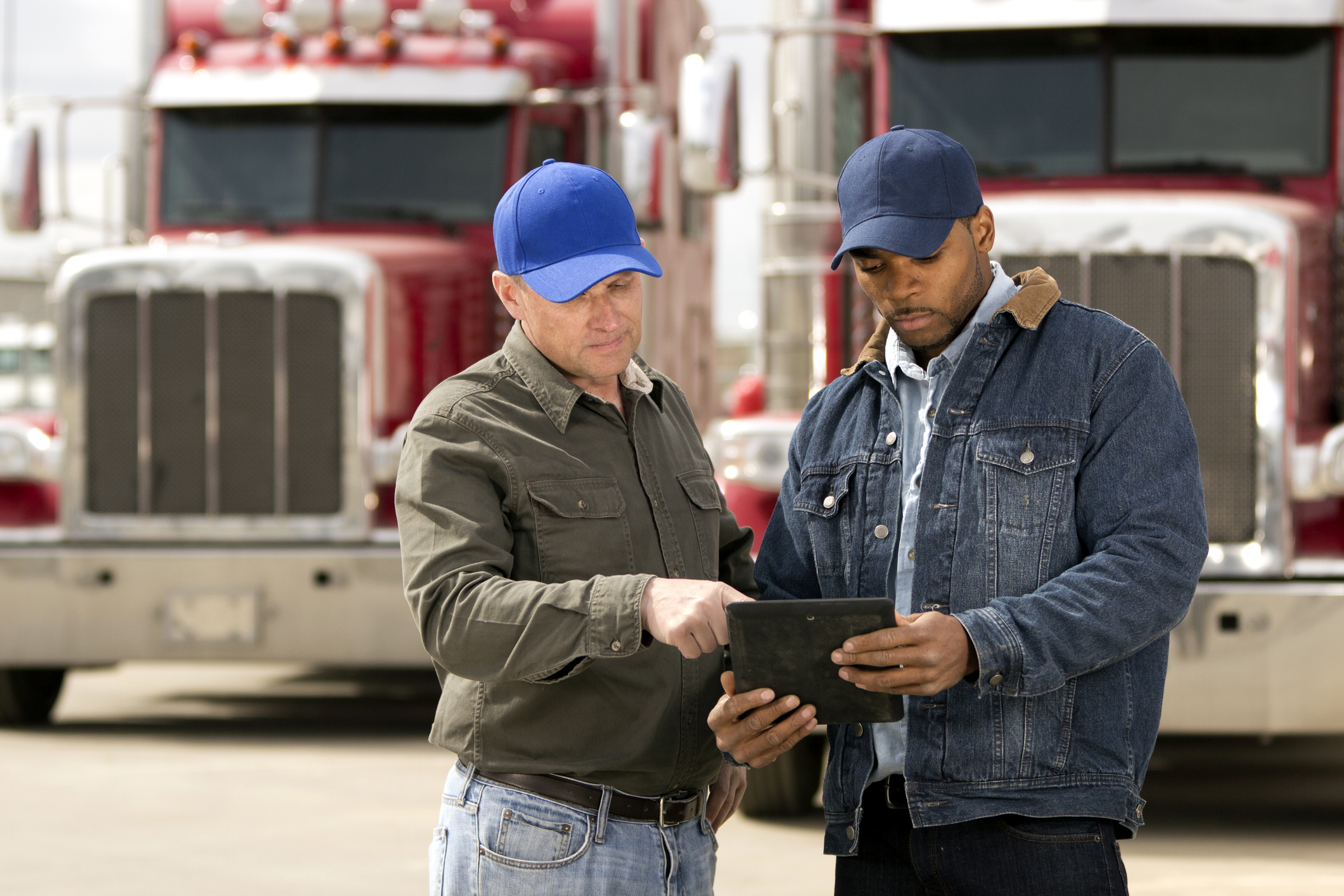 A royalty free image from the trucking industry of two truck drivers having a meeting using a tablet computer.