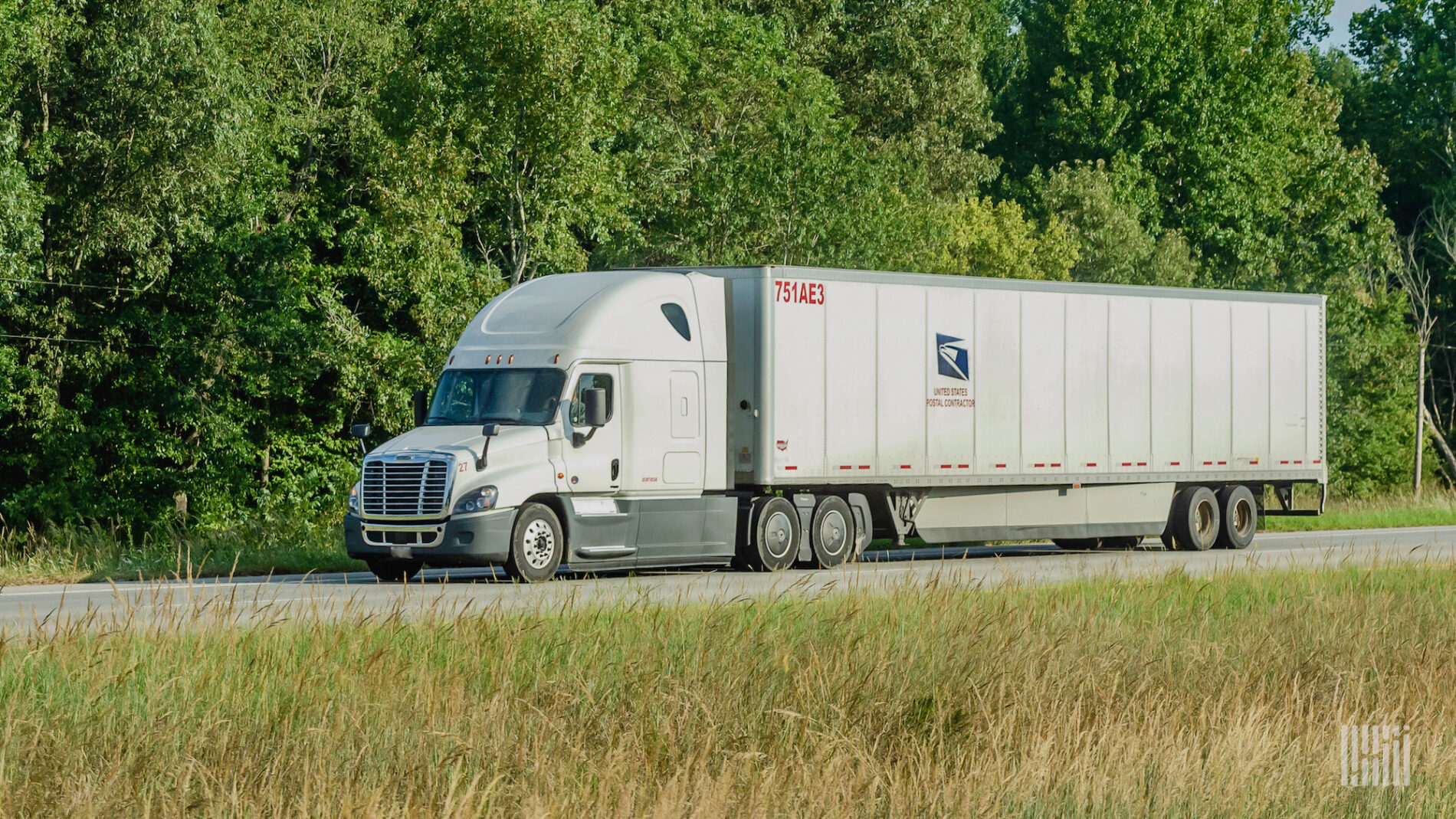 A commercial truck pulling a trailer that says United States Postal contractor.