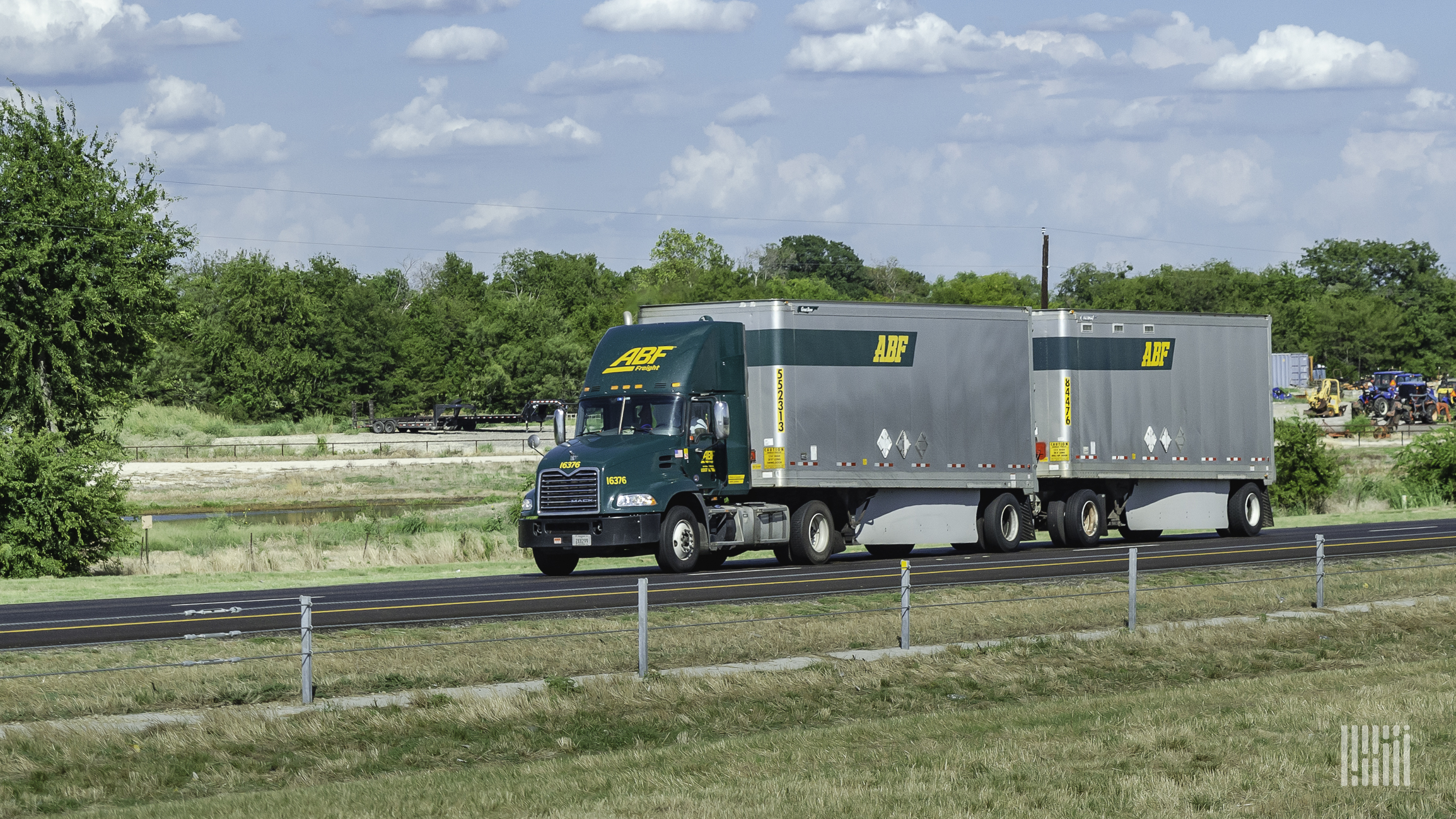 A green ABF Freight tractor pulling two silver ABF Freight trailers