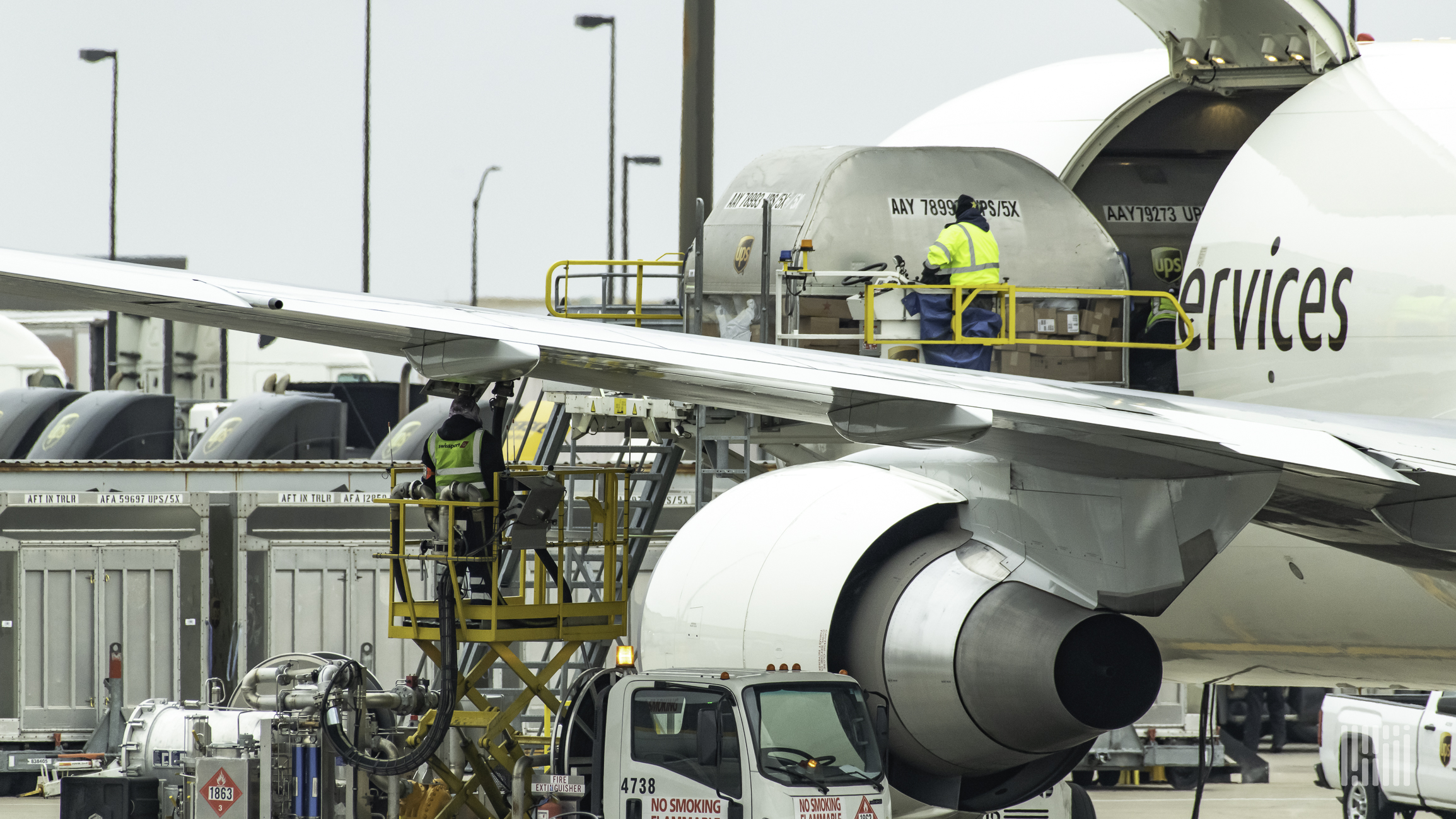 A jet being loaded with cargo and getting refueled at an airport.