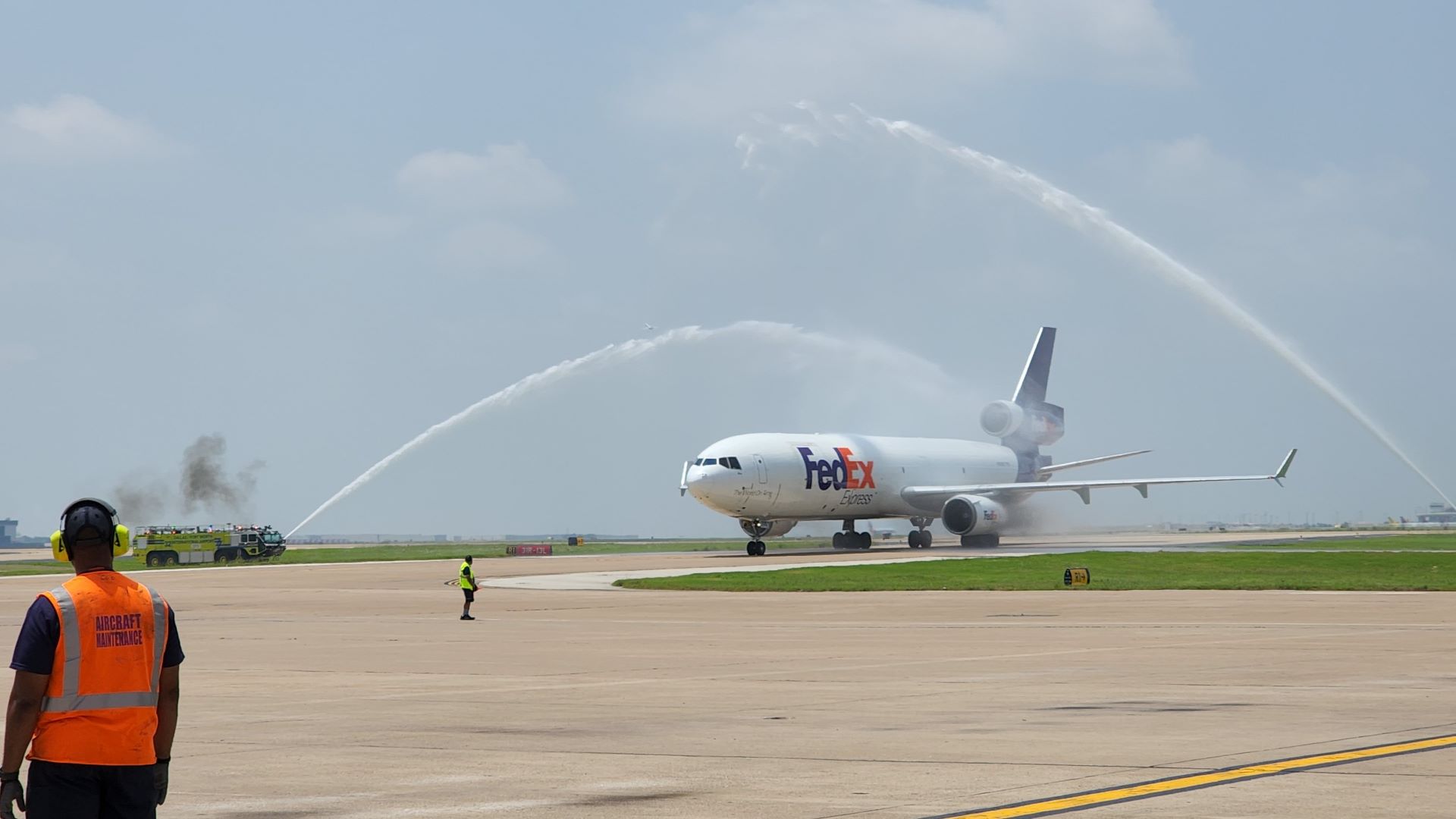 A white FedEx plane goes under water cannon streams in airport welcome.