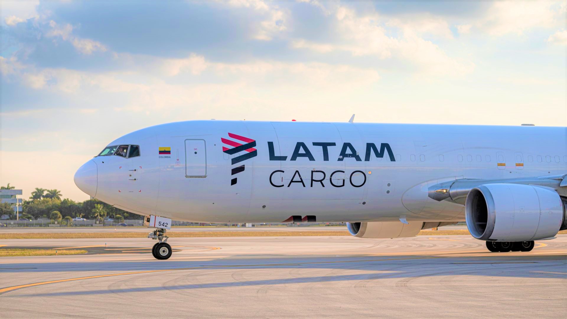 A white cargo jet with blue-and-red LATAM logo. Close up side view of cockpit and front.