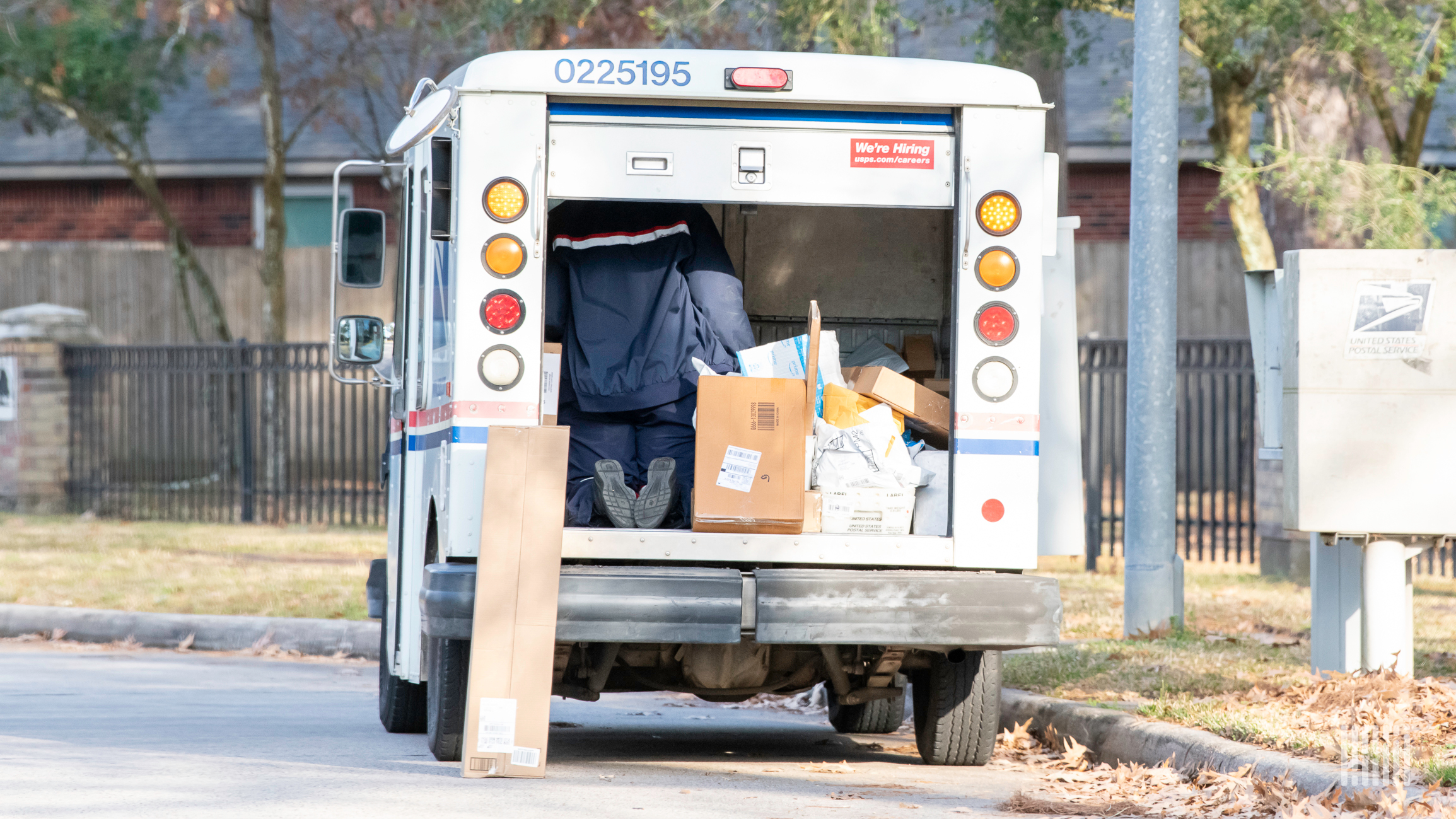 Driver in back of Postal Service vehicle unloading packages