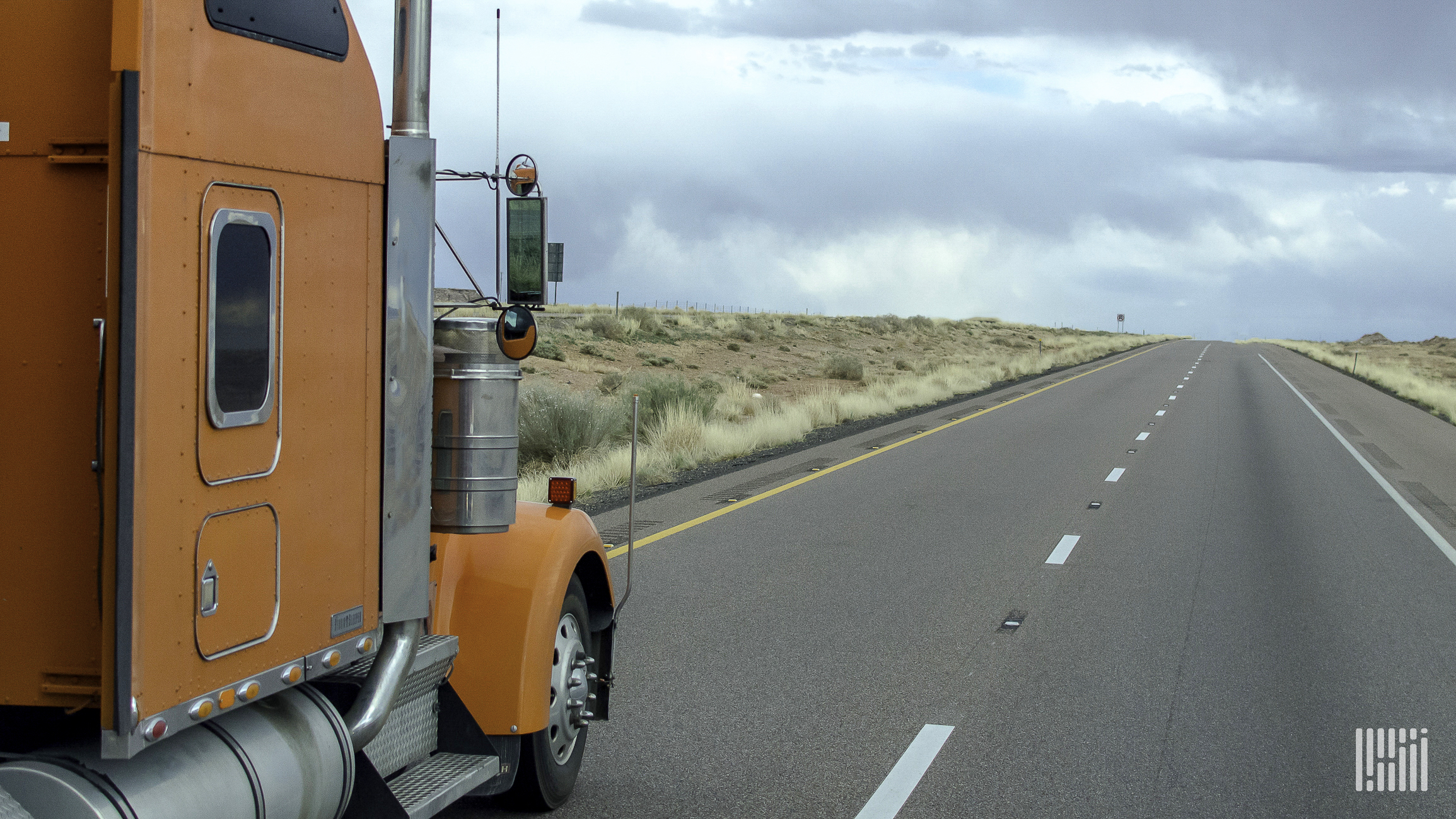An orange truck on a highway.