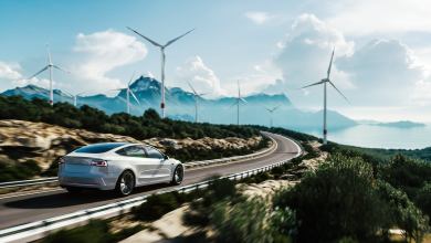 EV electric vehicle driving down road with sun and sunlight overhead