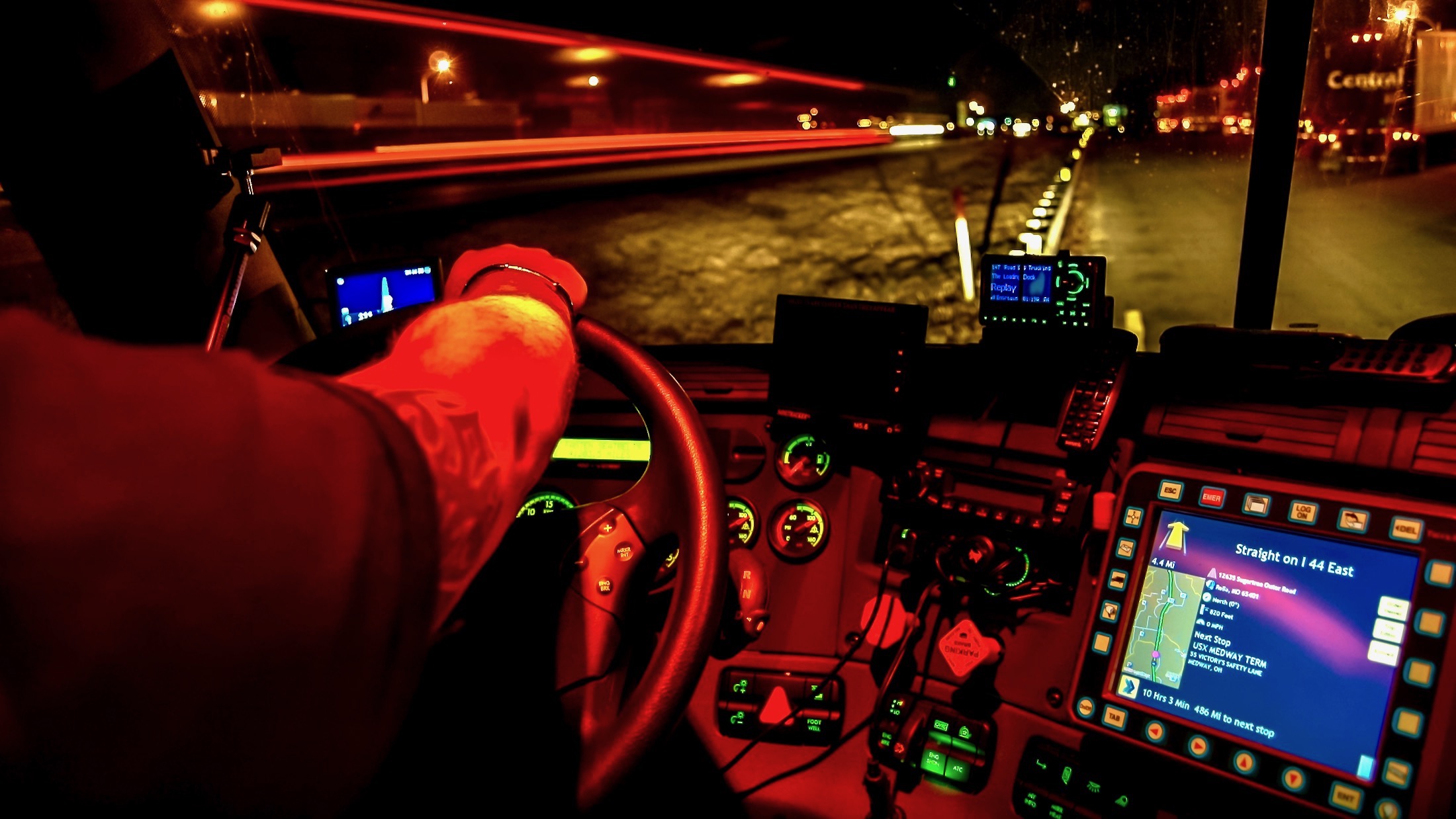 A driver grips the steering wheel of a Freightliner truck.