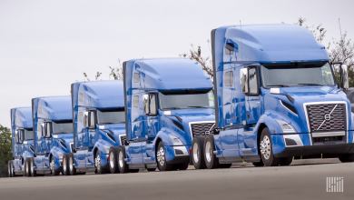 Row of four bluish purple Volvo Class 8 trucks