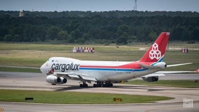 A white Cargolux jumbo jet with red tail prepares to take off. View from the rear.