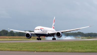 A large jetliner touches down on runway with smoke appearing from tires.