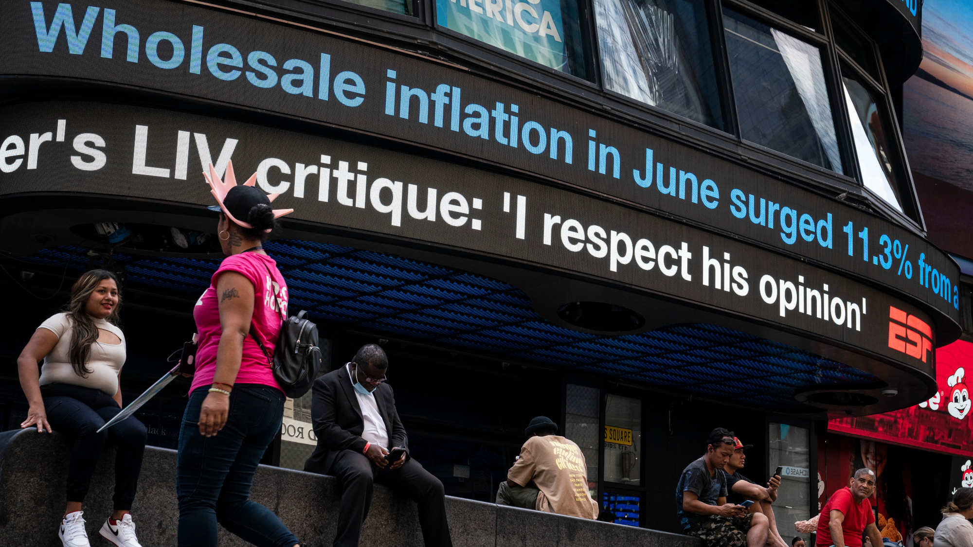 A news ticker displays inflation number in Times Square