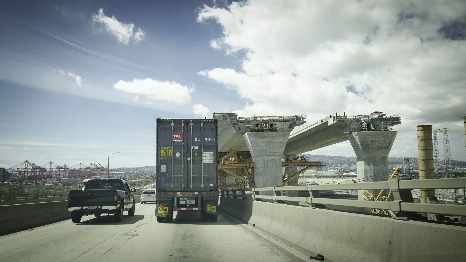 Truck passing by bridge under construction.