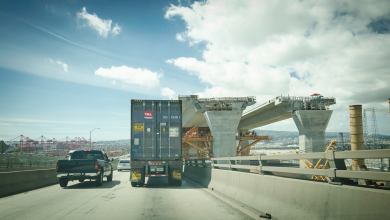 Truck passing by bridge under construction.