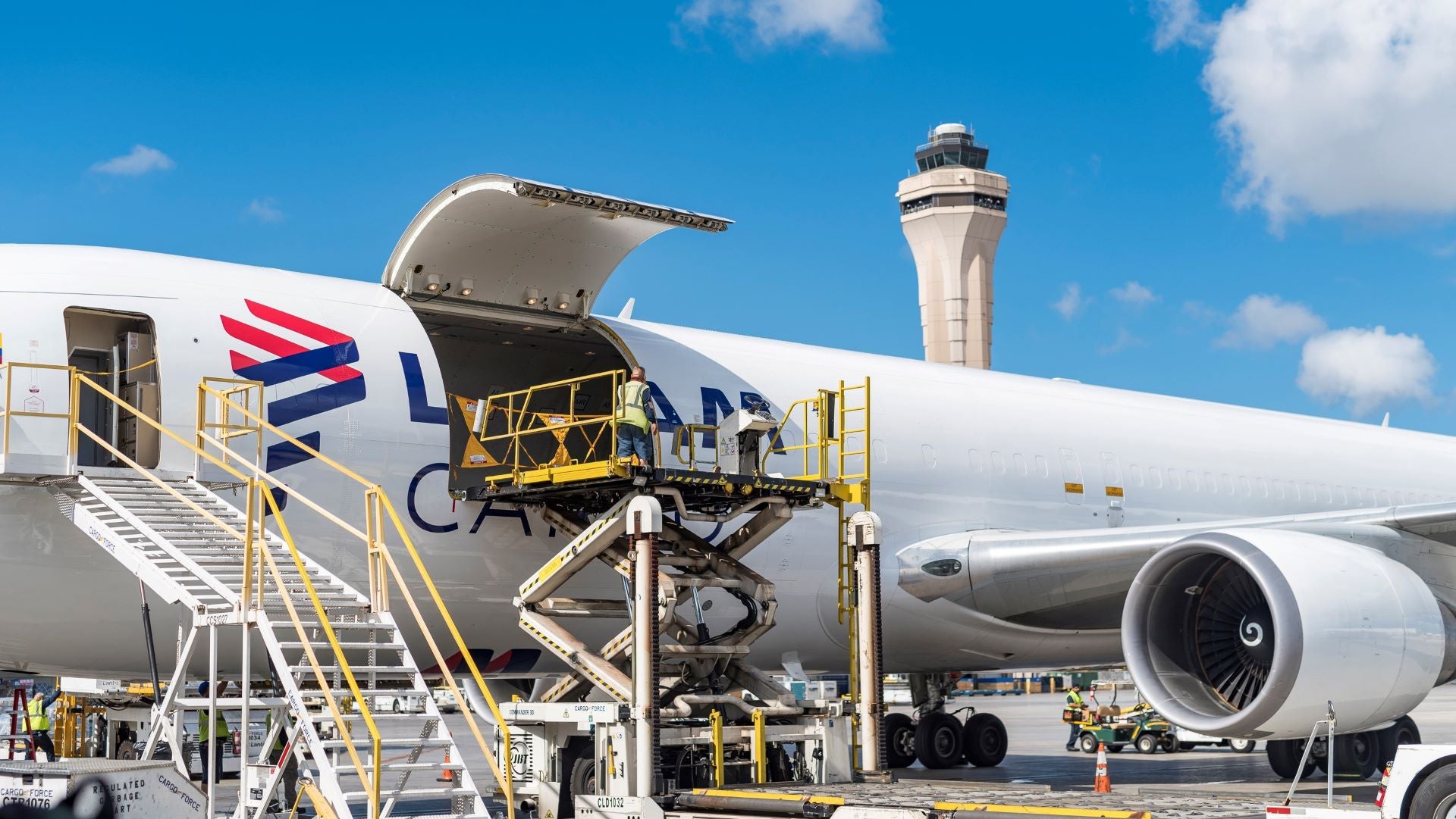 A cargo pallet on a lift being moved through the side cargo door of a big, white jet.