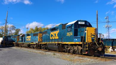 A CSX locomotive pulls railcars down a railroad track.