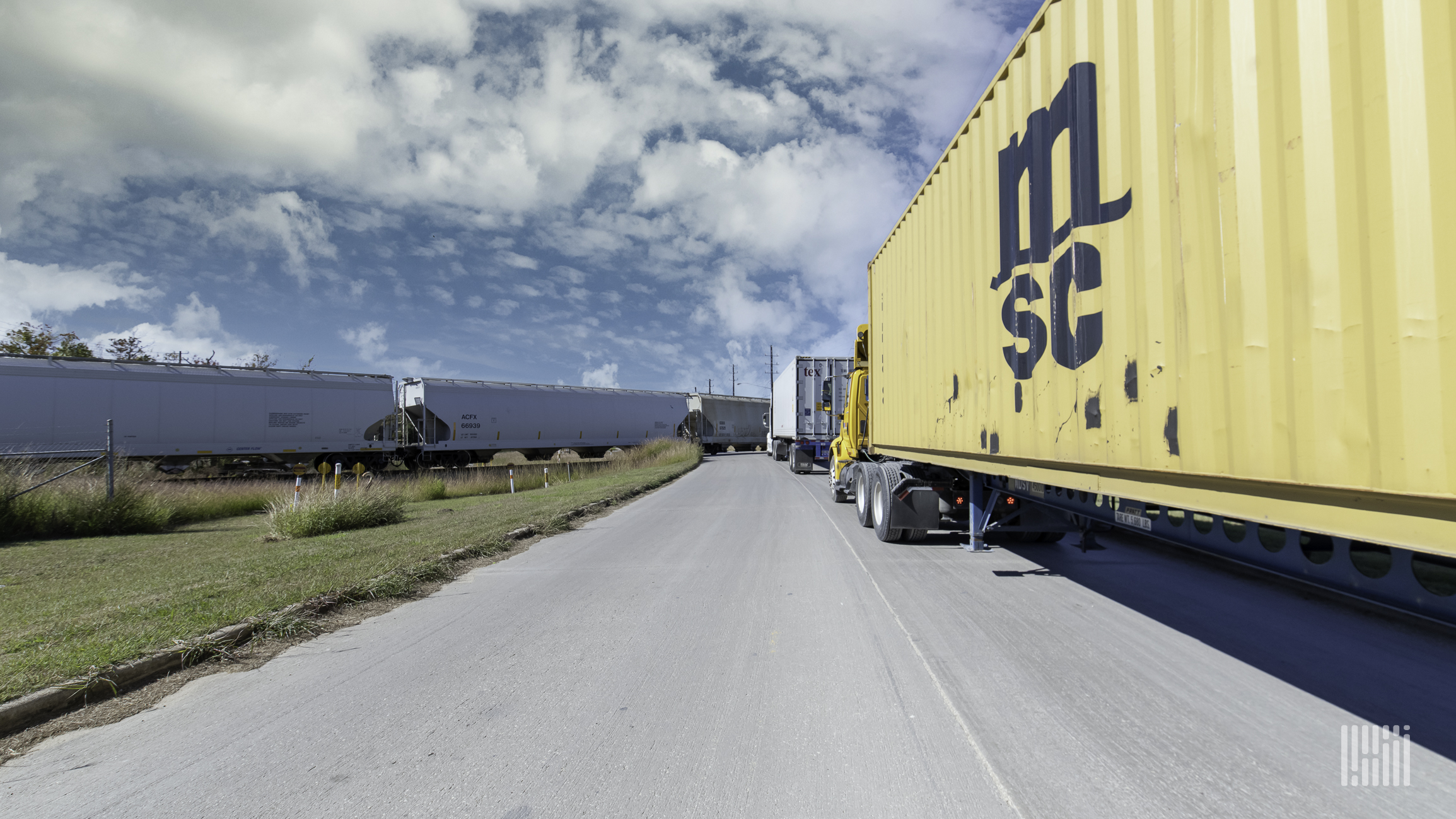 Drayage trucks waiting at a rail crossing