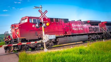 A red train with the words "Canadian Pacific" on its side travels through a railroad crossing.