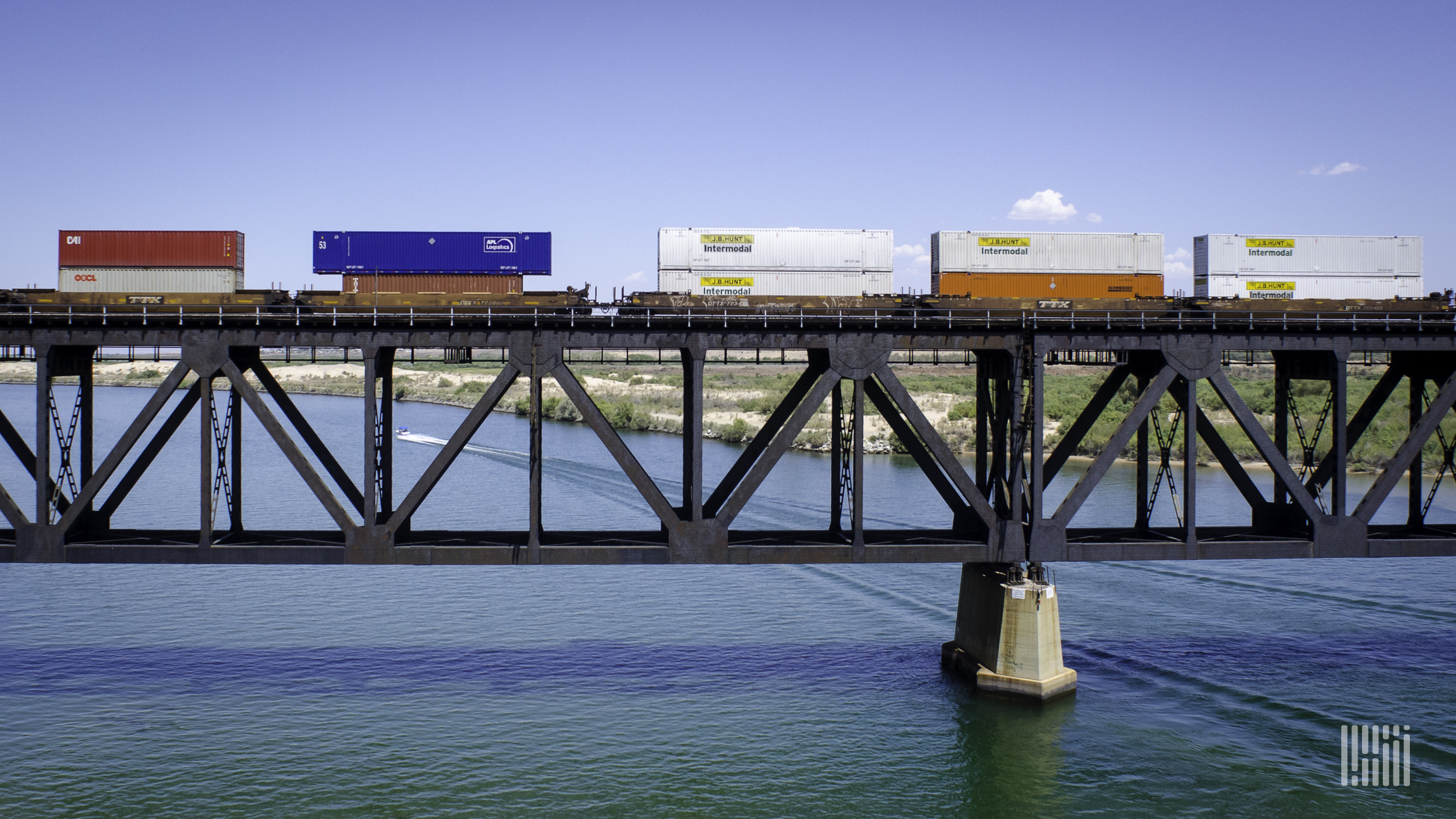 A train hauling intermodal containers travels on a bridge.