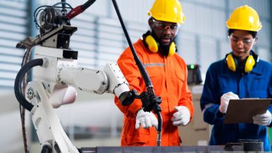 2 men standing next to manufacturing robot