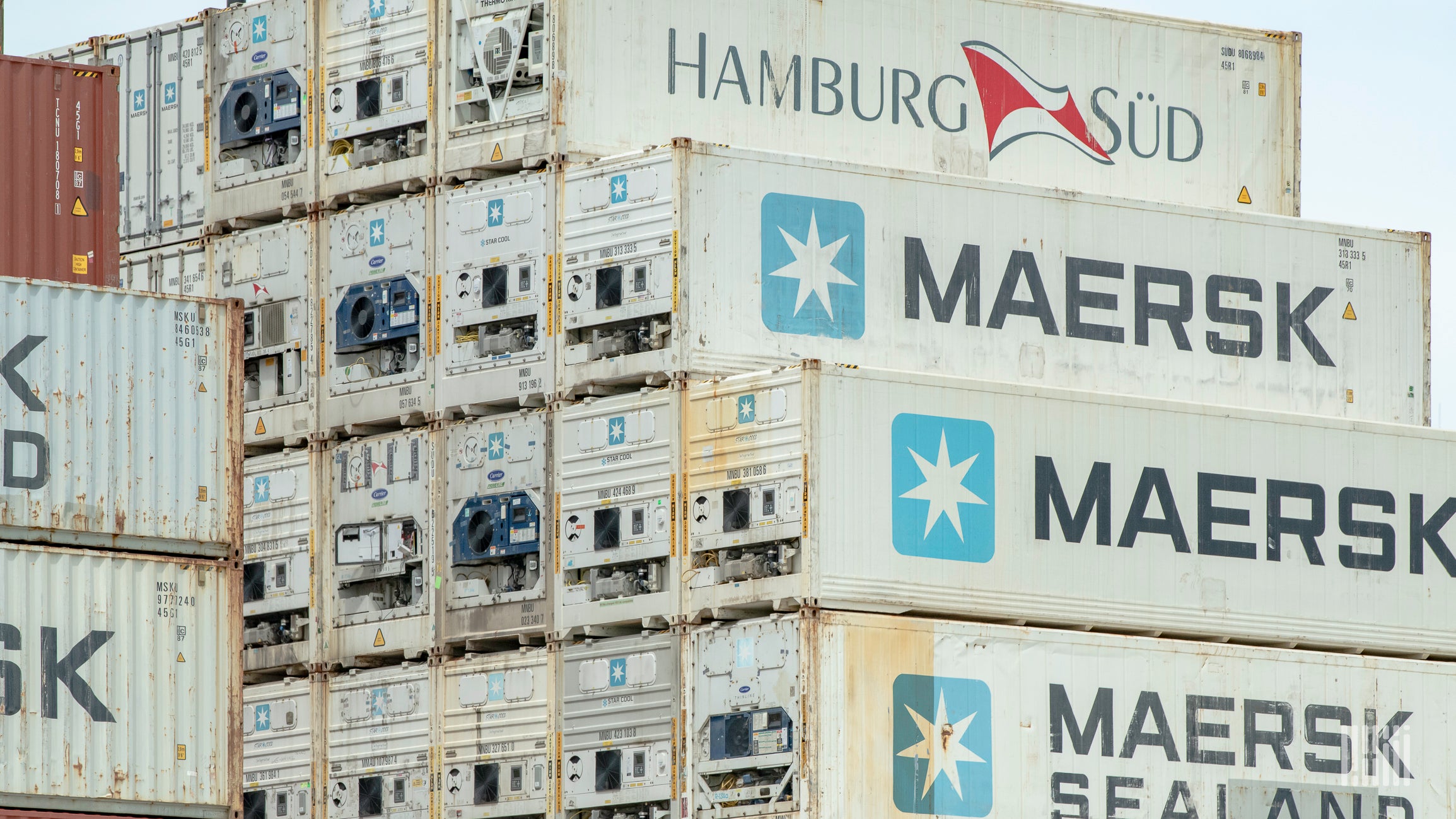 A stack of Maersk ocean shipping containers a port.