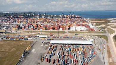 Semi trucks wait in lines to enter a maritime port.