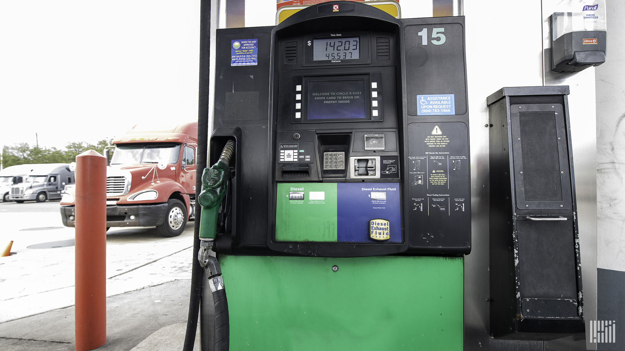 A red truck is behind a diesel fuel pump.