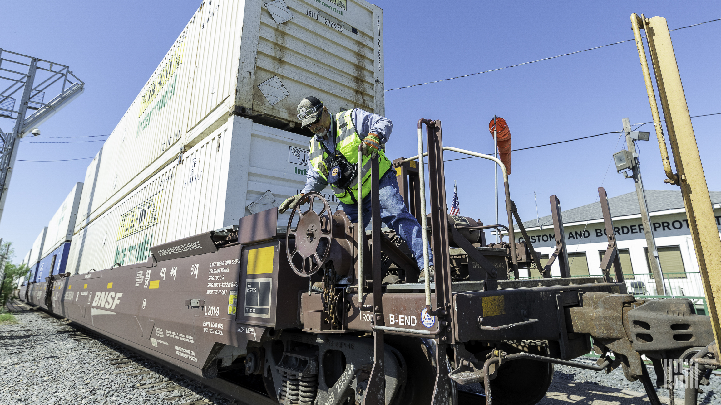 A man inspects a railcar carrying an intermodal container.