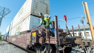 A man inspects a railcar carrying an intermodal container.