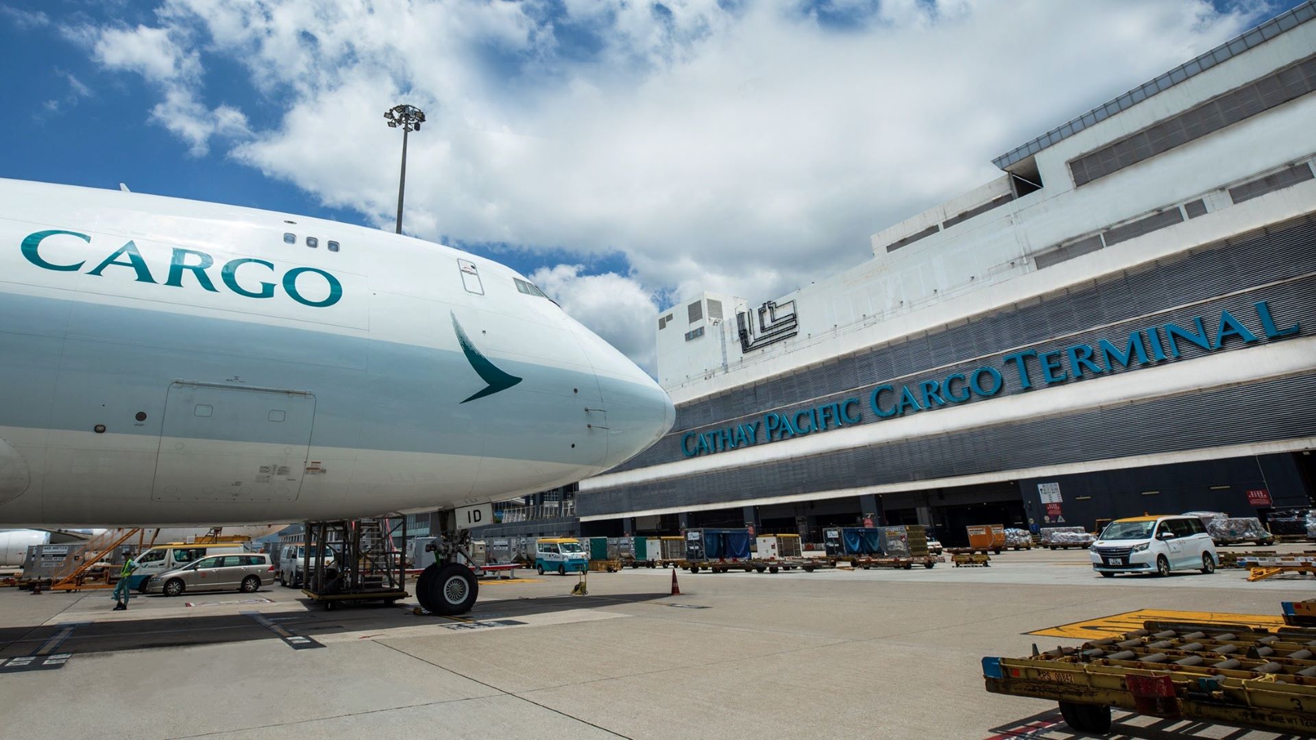 Front end of a large Cathay Pacific Cargo jet in front of the cargo terminal.