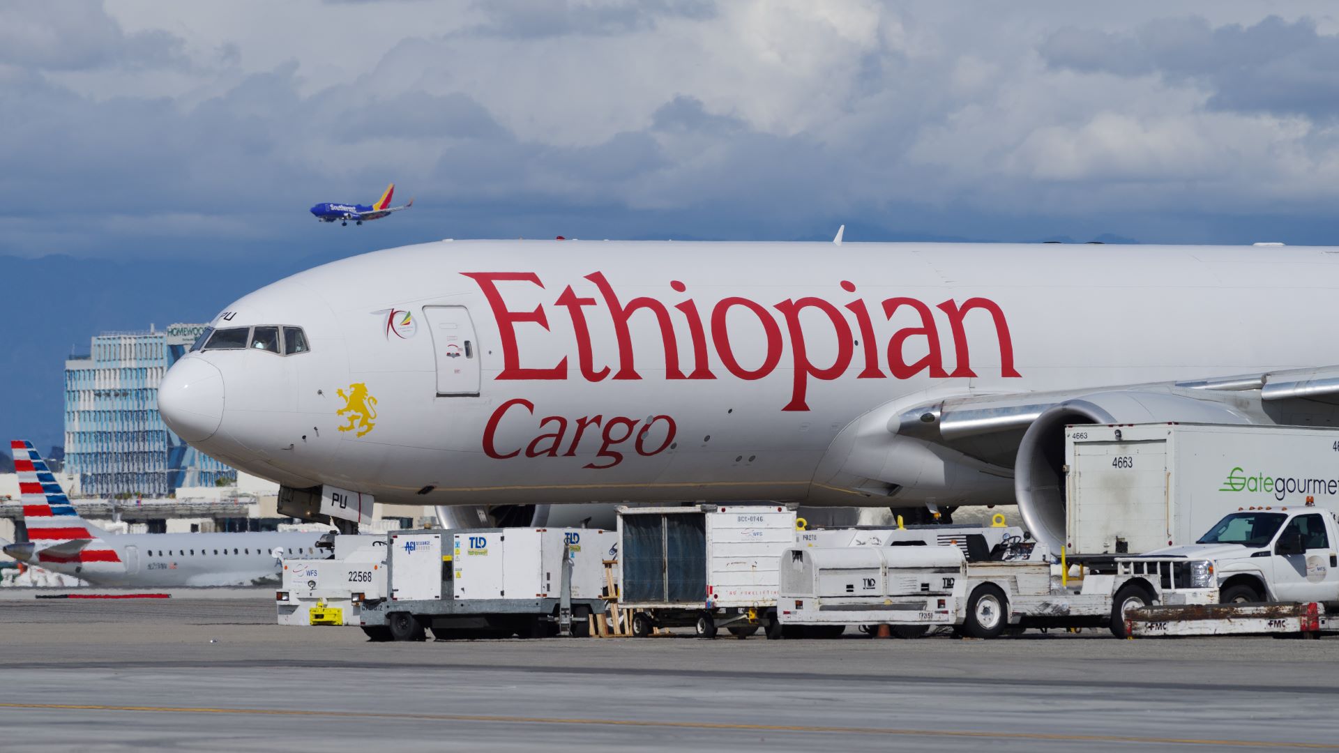 A large, white jet with Ethiopian Cargo label on the airport tarmac with loading equipment surrounding it.