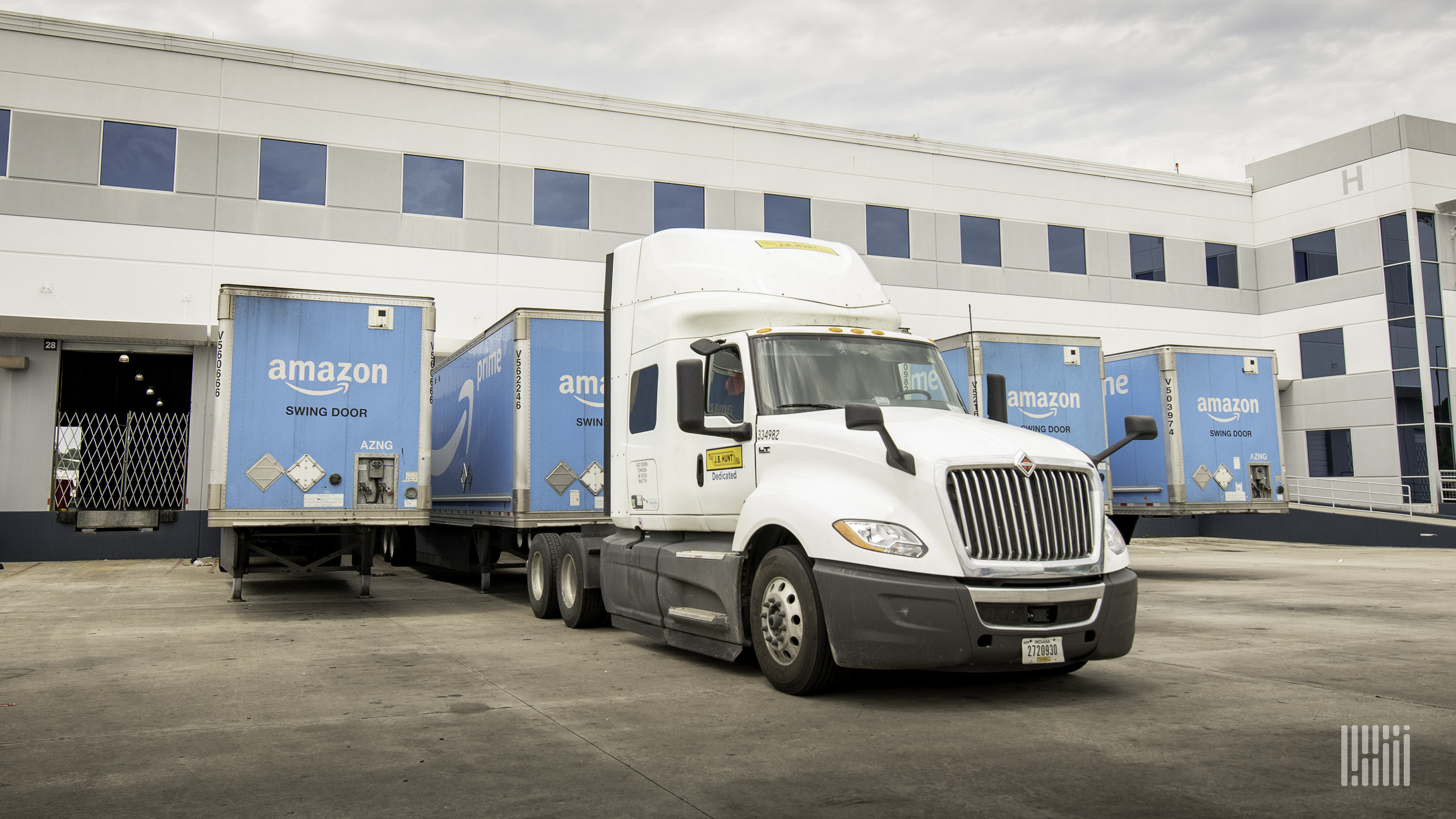 A tractor is picking up an Amazon trailer at a warehouse.