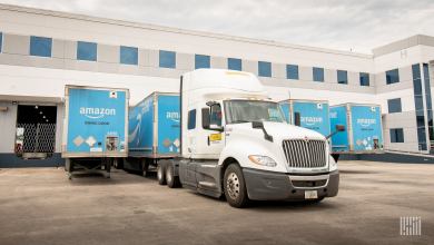 A tractor is picking up an Amazon trailer at a warehouse.