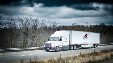 A white Heartland Express tractor-trailer on a highway