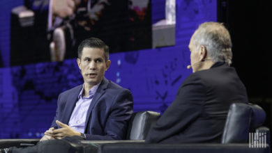 Two white guys discussing issues on stage at a conference.