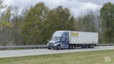 A blue Werner tractor pulling a white Werner trailer on a highway