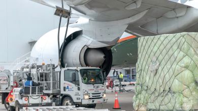 A cargo pallet and a fuel truck under the wing of a large jet.