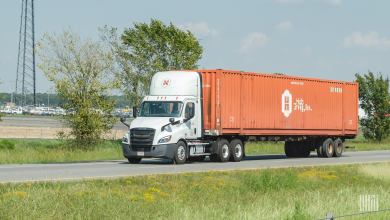 A white Hub Group truck pulling an orange 53-foot container