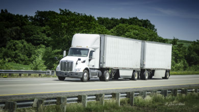 A white tractor pulling two white LTL trailers