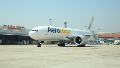 A white jet with AeroLogic logo on the cement tarmac at Hanoi airport, with cargo terminal in background.