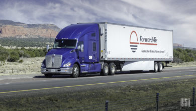 A blue tractor pulling a white Forward Air trailer