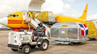 A bright yellow DHL plane with cargo door open as it gets unloaded.