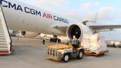 A tug vehicle pulls a pallet of cargo after being unloaded from a CMA CGM Air Cargo plane.