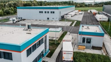 Warehouse buildings with DB Schenker trucks in the parking area.