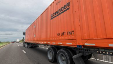A Schneider truck and chassis hauling an orange Schneider intermodal container