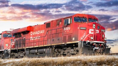 A Canadian Pacific train moving across a field at sunset.