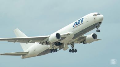 A white jet with ATI logo in the air after takeoff with wheels down.